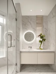 Modern minimalist white marble bathroom with a round mirror and glass shower door.