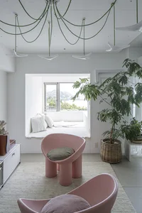A modern living room with minimalist furniture and a neutral color palette, featuring large windows with a view of greenery a
