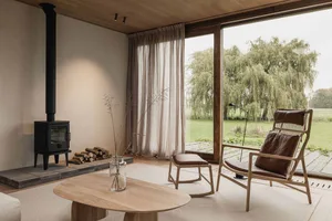 Contemporary minimalist living room featuring wood finishes, a floor-to-ceiling window overlooking greenery, a sleek coffee t