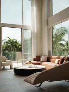 Contemporary living room with glass walls, leather furniture, and fabric textures