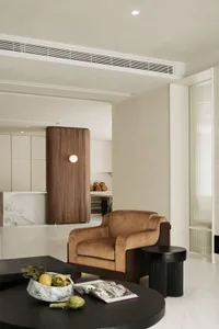 A modern living room with a sand brown leather couch, black round coffee table, and minimalist decor.