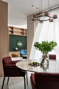 A dining room with a modern, minimalist design featuring a marble table, leather chairs, and a minimalist chandelier.