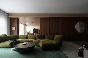 A modern living room with a green velvet sofa and wall paneling