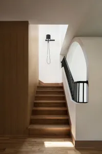 Modern interior design featuring wooden staircase with black railings.