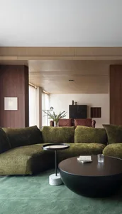 Modern living room with a green upholstered couch, circular coffee table, and minimalist decor.
