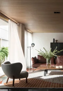 A modern minimalist living room with wooden flooring, a cozy sofa, a unique coffee table, and a decorative plant in a vase.
