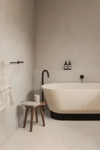 A minimalist bathroom featuring a terrazzo bathtub and stool.