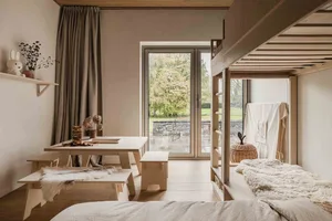 Minimalist bedroom with wooden furniture and a window overlooking a garden.