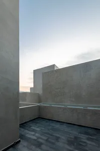 A minimalist rooftop exterior featuring a concrete structure with a clear sky background.