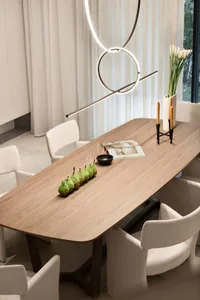 A modern dining room featuring a wooden table with a minimalist vase and decorative items.
