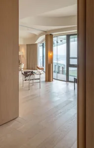 A modern living room featuring hardwood flooring, contemporary furniture, and large windows with a view.