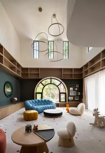 A modern living room featuring a blue sofa, round tables, and glass windows.