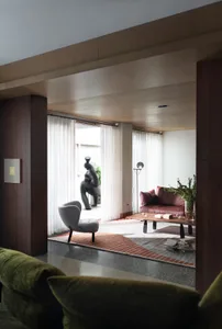 A modern living room with a wooden sofa, coffee table, and decorative elements like a vase and greenery.