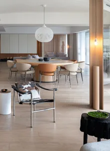 Modern living room featuring wooden flooring, round dining table, and contemporary armchair.