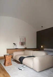 A modern minimalist bedroom with a grey sofa, minimalist decor, and a simple color palette.