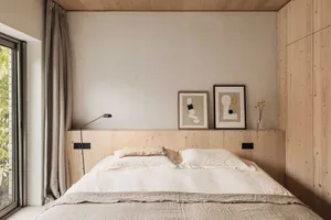 A modern minimalist bedroom with a wooden headboard and abstract art.