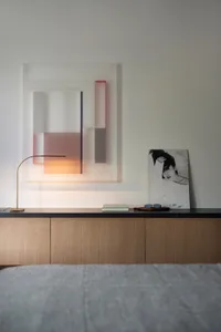 A minimalist bedroom featuring a colorful geometric wall artwork and wooden cabinets.