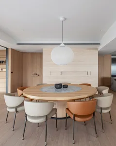 Modern dining room featuring a round wooden table with a marble insert centerpiece, surrounded by stylish chairs and natural 