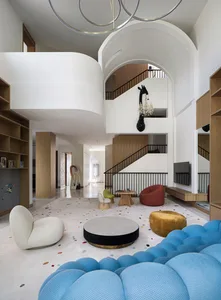 A modern living room with mixed materials including a round coffee table and a large blue cushioned seating area.