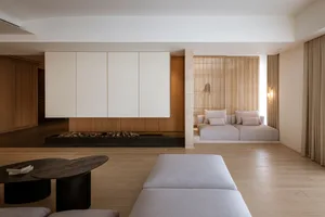 Modern living room featuring two white sofas with light-colored cushions against a wooden background with white paneling on t