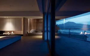 Modern living room featuring wooden flooring, contemporary furniture, and a view of mountains through large windows.