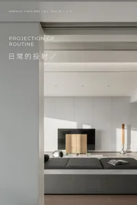 A minimalist living room with a grey sofa, a wooden cabinet, and a television.