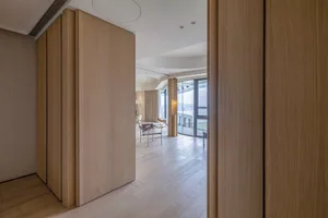 Modern minimalist living room featuring wood paneling and a light-colored floor.