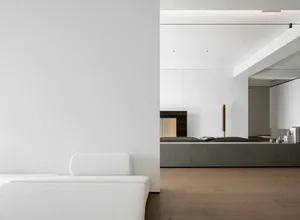 Modern minimalist living room with concrete walls, wooden floors, and metallic accents.
