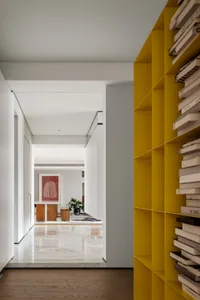 A modern minimalist living room showcasing vibrant yellow shelving units filled with books.