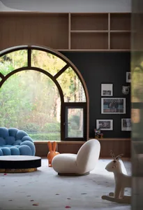 A modern playroom featuring wooden furniture and a large window with an arched design.