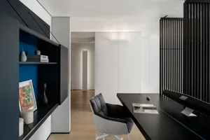 Modern home office with a sleek black desk, white chair, and minimalist design elements.