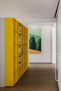 A modern interior featuring a yellow bookshelf filled with books.