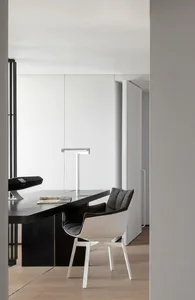 A modern, minimalist office space with a sleek black desk and contemporary chair.