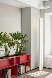 Modern interior featuring a metal red shelf with green plants, a concrete wall, and wooden flooring.