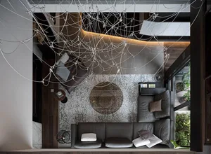 Top-down view of a modern living room with a black leather sofa, abstract rug, and minimalist decor.