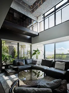 Modern living room with marble accents, glass windows, and black leather sofa