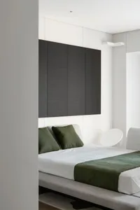 A modern minimalist bedroom with white walls and black cabinetry.