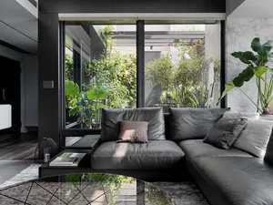 Contemporary black leather sectional sofa adorned with textured cushions, situated in a well-lit, contemporary living room fe