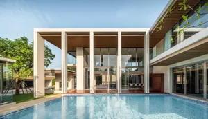 A modern residential building with large glass windows, concrete pillars, and wood accents.