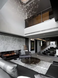 A sleek modern living room featuring marble accents, glass elements, and metal finishes.