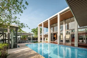 A modern residential house with concrete walls, large glass windows, and a wooden deck
