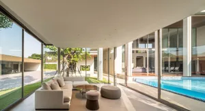 Modern living room with a glass wall and a comfortable seating area.