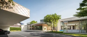 Modern house exterior made of concrete, glass, and surrounded by greenery.