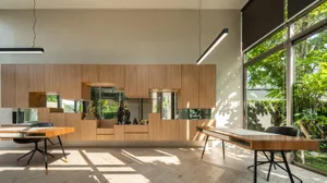 Modern kitchen and dining area with wood grain texture, minimalistic design, and large windows allowing natural light to ente