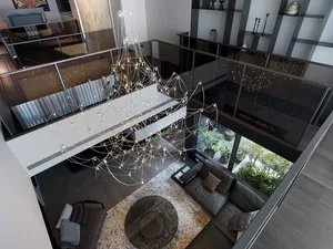 Modern living room with a glass and metal chandelier, a leather sofa, and a circular glass table.