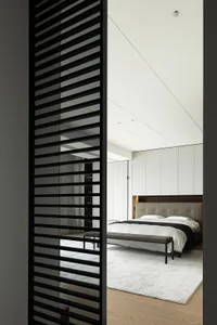 Modern minimalist bedroom with a white bed, grey headboard, and metal frame furniture.