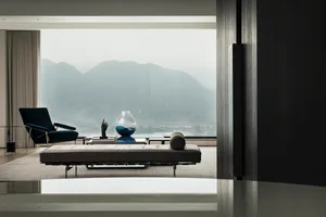 A minimalist living room with a view of distant mountains through a large glass window.