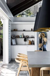 A modern dining area featuring concrete furniture, wooden chairs, and a skylight.
