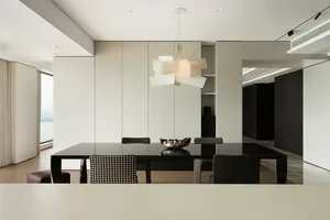 Modern dining room featuring white walls and black dining table with contemporary lighting fixtures.