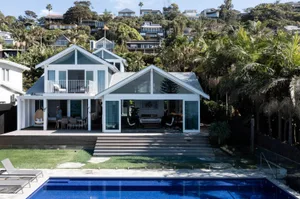 A modern white-rendered house with a pool and outdoor seating area.